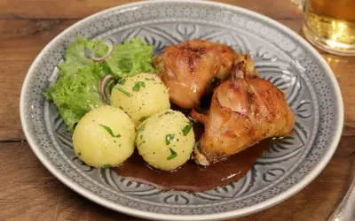 Saftiger Hasenbraten Hausfrauenart mit Klößen, Salat und dunkler Soße auf einem gemusterten Teller.