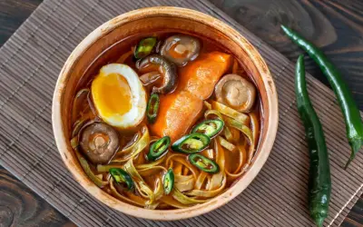 Eine Schüssel Ramen mit Ei, Pilzen und Chili. Der würzige Sud weckt die umami zunge und verspricht ein intensives Geschmackserlebnis.