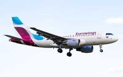 Samolot Eurowings z wysuniętym podwoziem na tle nieba.