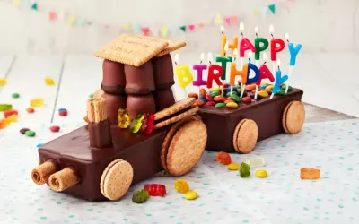 Schokoladen-Traktor-Torte, die man leicht selber machen kann, mit bunten Kerzen und Gummibärchen verziert.