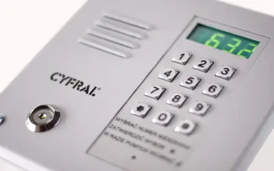 Panel domofonu Cyfral z klawiaturą numeryczną i wyświetlaczem. Instrukcja podpowiada, jak ściszyć domofon, wybierając numer mieszkania i potwierdzając go.