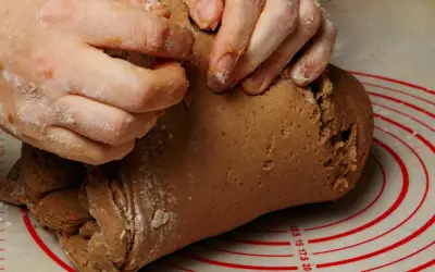 Dłonie zagniatają ciasto na pierniki. Tak, ciasto na pierniki może leżeć w lodówce, by nabrało smaku.