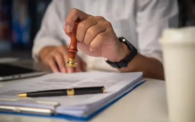 Dłoń z pieczęcią nad dokumentem. Czy umowa zlecenie chroni przed komornikiem?