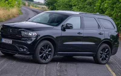 Czarny Dodge Durango 3.6 na krętej drodze, otoczony zielenią.