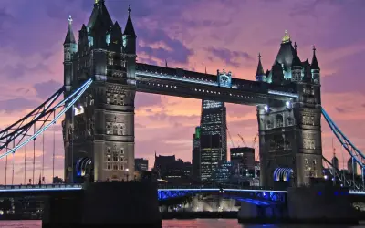 Wieczorny widok na Tower Bridge, jeden z najpiękniejszych zabytków w Londynie, z fioletowym niebem w tle.