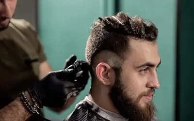 Un homme se fait couper les cheveux en coupe mohawk court par un coiffeur.