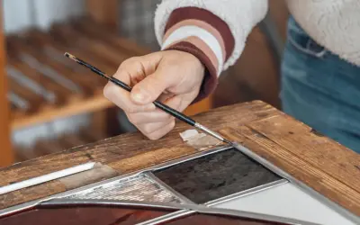 Main d'un artisan travaillant sur un vitrail, un exemple de métiers rares et recherchés.