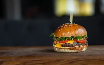 Apetyczny hamburger z sezamem na drewnianym blacie.