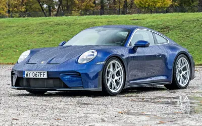 Niebieskie Porsche 911 na mokrej nawierzchni, z kroplami deszczu na karoserii. Czy to najtańsze porsche, jakie można znaleźć?