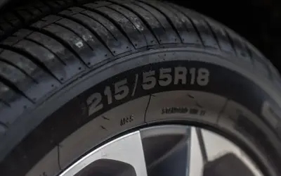 Zbliżenie na oponę z widocznym rozmiarem 215/55R18. Data produkcji opony jest kluczowa dla jej bezpieczeństwa.