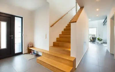 Moderne Ideen für den Hauseingang: Eine Holztreppe mit integrierter Sitzbank und Schuhablage lädt zum Eintreten ein.
