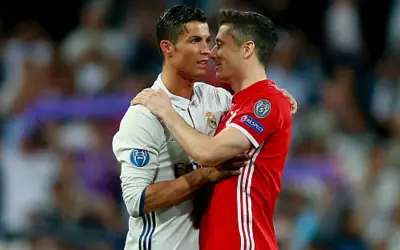 Dwóch piłkarzy, Cristiano Ronaldo i Robert Lewandowski, przytulają się. Lewandowski, z jego złotym butem, wydaje się być w dobrym nastroju.