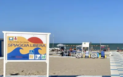 Cartello "Spiaggia Libera" a Porto San Giorgio, con simboli per accessibilità e famiglie.