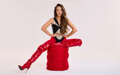Blanka Stajkow w błyszczących czerwonych kozakach i odważnym body, pozuje z przymrużeniem oka. Jej utwory często inspirowane są modą.