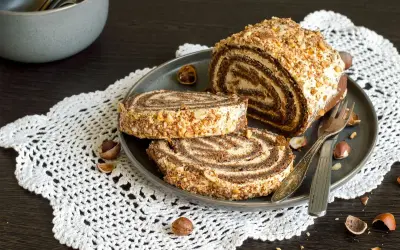 Un delizioso rotolo alla Nutella, ricoperto di granella di nocciole, pronto per essere gustato.