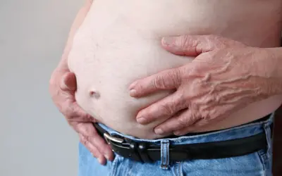 Osoba z zaawansowaną marskością wątroby, widoczny duży brzuch i dłonie obejmujące go.