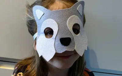 Dziecko w szarej masce wilka, idealnej do zabawy w leśniczego. Proste wykonanie, jak zrobić maskę wilka krok po kroku.