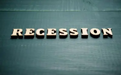 Drewniane litery układają słowo "RECESSION". To pojęcie ekonomiczne, które opisuje spowolnienie gospodarcze.