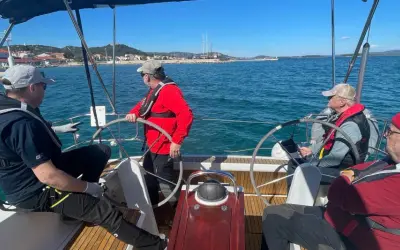 Uomini imparano a navigare durante un corso skipper, con un istruttore che guida il timone.