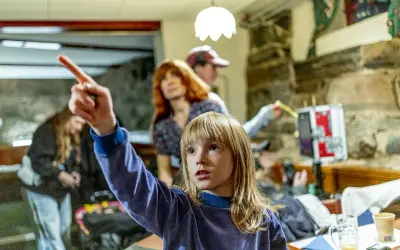 Barn pekar mot något spännande bakom filmerna. En kvinna med rött hår och en person med keps tittar också.