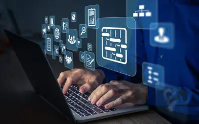 Dłonie pracują na laptopie, nad którym unoszą się ikony symbolizujące integrację systemów, zarządzanie projektami i współpracę.