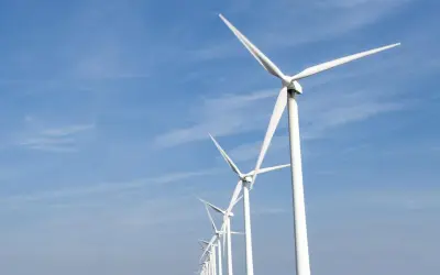 Reihe von Windrädern unter blauem Himmel, ein Symbol für Frankreichs Engagement für erneuerbare Energien.