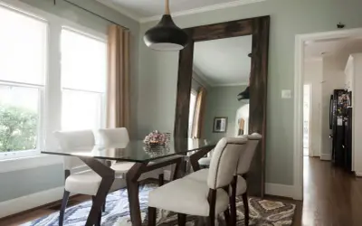 Un grand miroir rustique reflète la salle à manger, offrant une idée de où mettre un miroir dans une salle à manger pour agrandir l'espace.