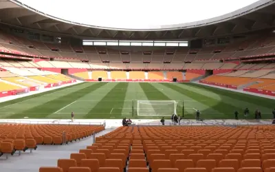 Pusta trybuna stadionu La Cartuja z pomarańczowymi siedzeniami i zieloną murawą.