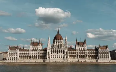 Majestatyczny Parlament w Budapeszcie i okolice, odbijający się w spokojnej wodzie Dunaju.