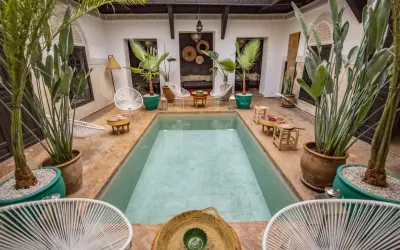 Ein Riad in Marokko: Ein Innenhof mit Pool, Pflanzen und Sitzgelegenheiten, typisch für marokkanische Architektur.