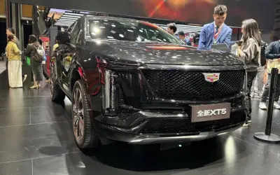 Elegancki, czarny Cadillac XT5 na wystawie. Ludzie oglądają nowy model, który przyciąga uwagę swoim designem.