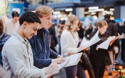 Unga människor skriver på papper vid ett event om framtida yrken att satsa på.