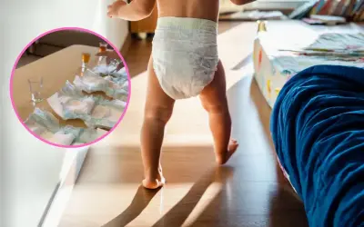 Dziecko w pieluszce idzie po pokoju. Na stole w okręgu leżą pieluchy i kieliszki.