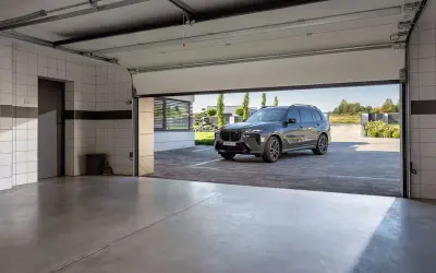 Nowa, nowoczesna brama garażowa strzela przy otwieraniu, odsłaniając luksusowego SUV-a na podjeździe.