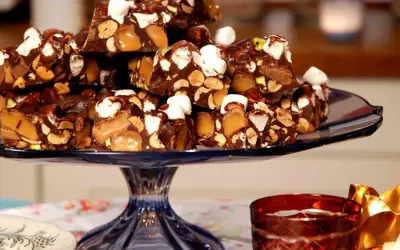 En hög med chokladbitar med nötter, karamell och marshmallows. En härlig rocky road-frestelse på ett blått fat.