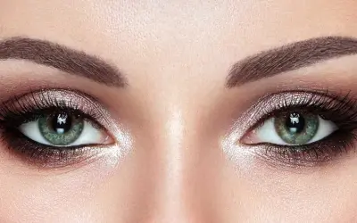 Ojos verdes deslumbrantes con un maquillaje ahumado y brillante, realzando su belleza natural.
