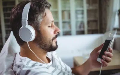 Mężczyzna w słuchawkach relaksuje się, słuchając muzyki na telefonie. Idealny sposób na darmową muzykę na telefon!