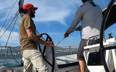 Due uomini in barca a vela, uno al timone, l'altro che regola le cime. Il **significato** di strambare è cambiare rotta.