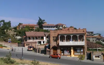Urokliwe uliczki Telavi, Gruzja, z tradycyjną architekturą i balkonami. Pomarańczowy samochód jedzie po drodze.