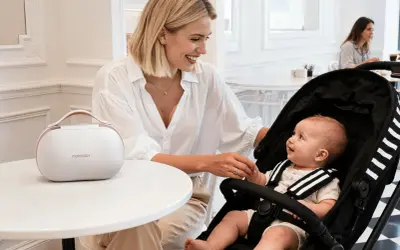 Uśmiechnięta mama z niemowlakiem w wózku, przygotowująca się do sylwestra. Obok biała torba Momcozy.