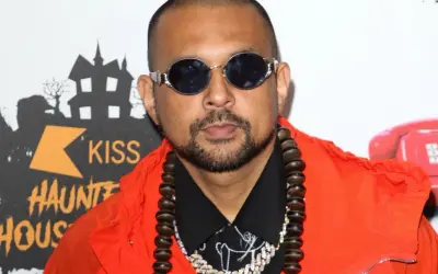 Sean Paul w pomarańczowej kurtce i okularach, gotowy do wykonania swoich hitowych sean paul utwory.