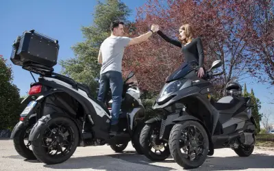 Pareja chocando las manos junto a sus Qooder QV3, listos para una aventura.