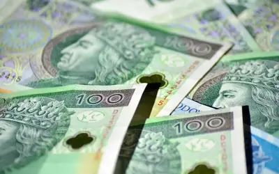 Stos banknotów 100 zł, symbolizujących zasiłek stały. Widać portrety królów i korony.