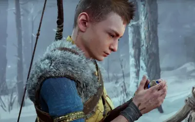 Atreus, zamyślony, trzyma w dłoni magiczny kamień. W tle zimowy las.