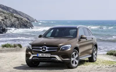 Brązowy, używany Mercedes GLC z salonu na tle morskiego krajobrazu. Idealny na wakacyjne wyprawy.