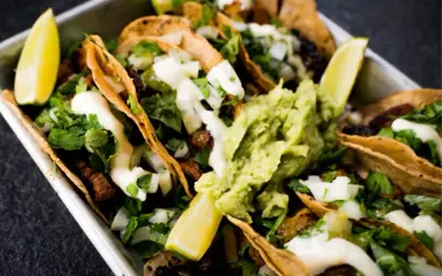 Saftige Tacos al Pastor mit Guacamole, Koriander und Limettenspalten.