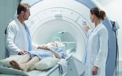 Lekarze nadzorują badanie rezonansem magnetycznym pacjentki leżącej w aparacie.