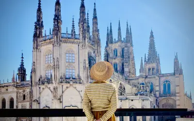 Una persona con sombrero admira la majestuosa Catedral de Burgos, considerada por muchos la mejor catedral de España, con sus imponentes agujas y detalles góticos.