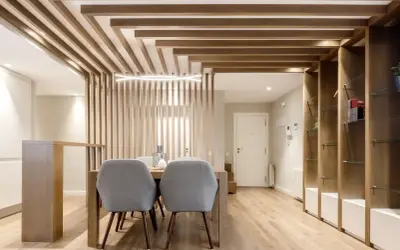 Comedor moderno con separador de listones de madera y estanterías. Preguntarse cuanto se tarda en tirar un tabique es irrelevante aquí.