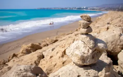 Kamienna wieża na skalistym brzegu, w tle turkusowe morze i piaszczyste plaże Pafos.